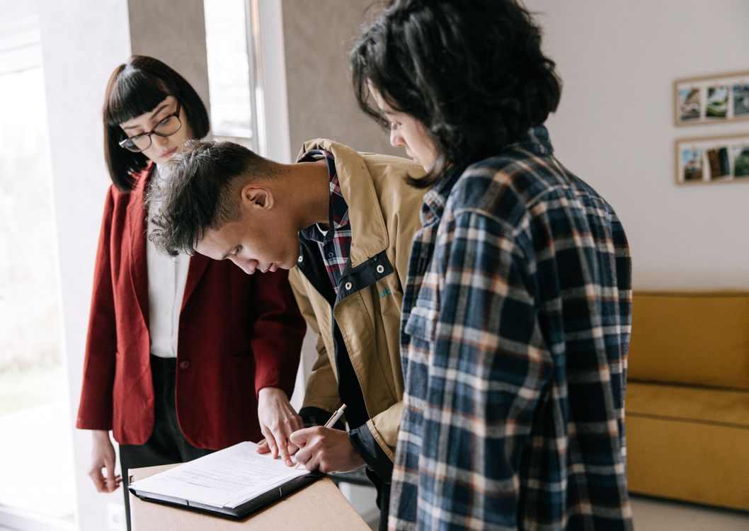 Homebuyers signing documents at a table with a real estate professional